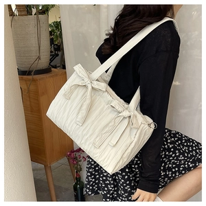 Pleated nylon bucket bag in cream white with a decorative bow on a female model