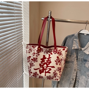Detail of cream knitted tote bag with red Double Happiness character and floral embroidery