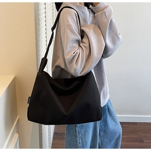 Detail of black canvas tote bag with white letter patch and adjustable shoulder strap