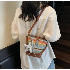 Detail of colorful woven bucket bag with silver starfish pendant worn crossbody