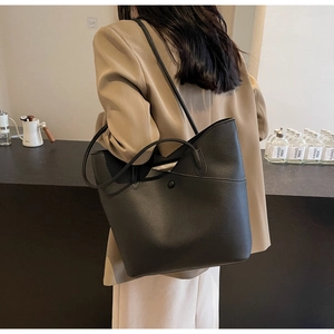 Detail of black pebbled leather tote bag with magnetic clasp pocket and dual straps