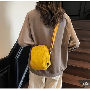 Détail de la sacoche jaune en nylon avec tissu texturé et logo latéral sur la sangle