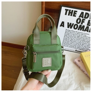 Detail of green waterproof nylon crossbody bag with adjustable strap and square logo