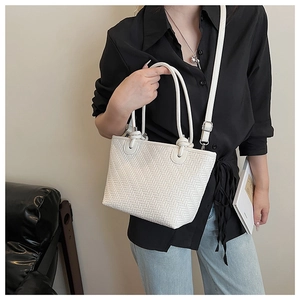 Detail of white woven tote bag texture with slim handles and adjustable shoulder strap
