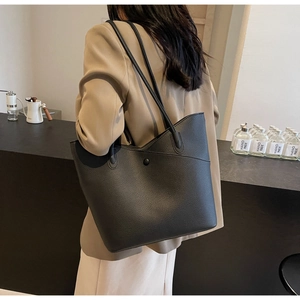 Detail of black lychee grain leather tote bag showing textured surface and shoulder strap