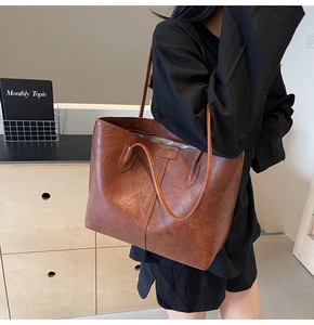 Deep brown retro leather tote bag styled by model in a modern minimalist indoor setting
