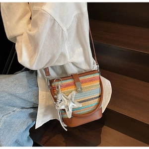 Detail of colorful woven bucket bag with brown leather trim and silver star pendant