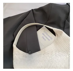 Detail der weißen Handtasche mit Fischgräten-Webmuster und weichem Tragegriff