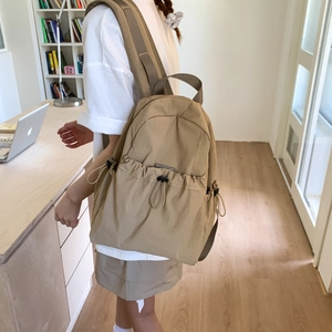 Detailed back view of a khaki nylon backpack showing wide cushioned shoulder straps on a model