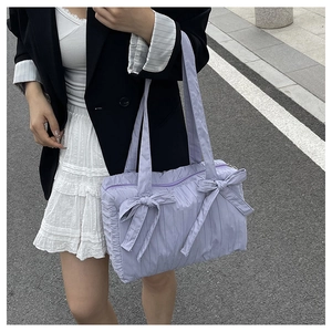 Detail shot of lavender pleated nylon bucket bag with decorative bows and shoulder strap