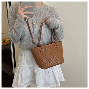 Detail showing woven texture and knotted handle on brown bucket bag in mirror selfie
