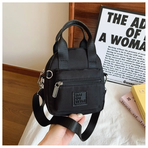 Detail of black waterproof nylon crossbody bag with front zipper and brand logo