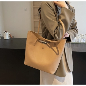 Detailed close-up of light brown lychee grain leather tote bag worn on shoulder
