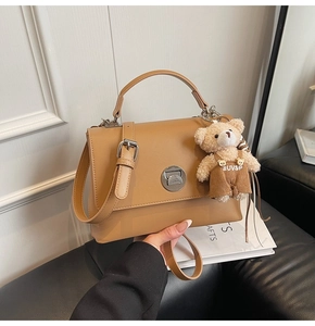 Close-up of brown vintage crossbody bag with silver buckle and plush bear charm detail