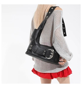 Detail of black punk shoulder bag featuring oversized silver buckle and metal eyelets