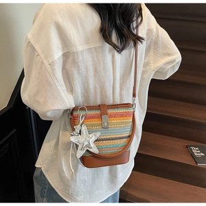 Close-up of colorful woven bucket bag with silver star charm and brown leather strap