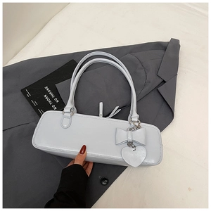 Detail of light blue baguette bag with ribbon bow, heart pendant on a grey blazer
