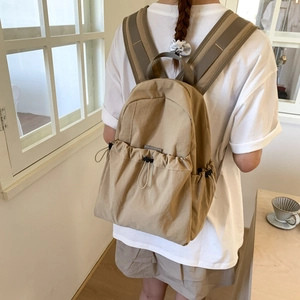 Detailed back view of a khaki nylon backpack with drawstring pockets for daily travel