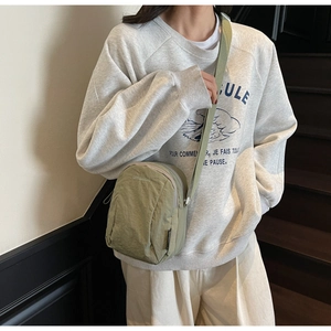 Détail d'un sac bandoulière en nylon vert pois avec logo de la marque et fermeture éclair
