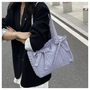 Detail view of lavender pleated nylon bucket bag featuring decorative ribbon bows