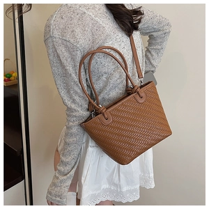 Close-up of caramel woven bucket bag with fine herringbone texture and slim strap