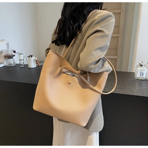 Large beige tote bag shown on shoulder in a minimalist cafe setting for daily commute