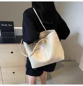 Detailed view of cream tote bag showing dual straps and pebble grain leather on model