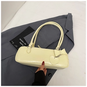 Detail of cream rectangular shoulder bag with bow and heart metal chain charm