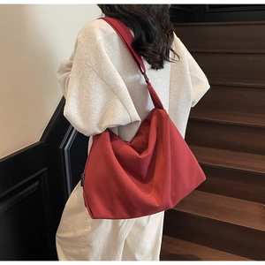 Detail of red slouchy canvas shoulder bag showing wide strap and large capacity