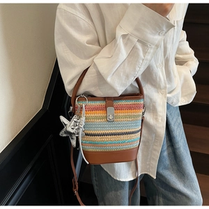 Close-up of rainbow woven bucket bag with brown leather base and silver star charm