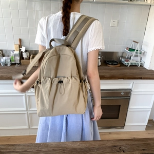 Khaki nylon backpack detail showing drawstring pockets and wide comfortable straps