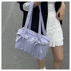 Detail of light purple pleated nylon bucket bag with two decorative bows and silver ring zipper