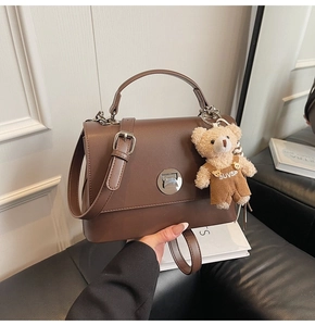 Detailed close-up of retro brown crossbody bag with silver clasp and plush bear charm