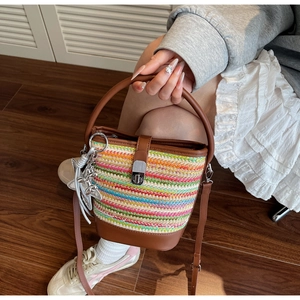 Detail of colorful woven bucket bag featuring brown leather trim and silver metal twist lock