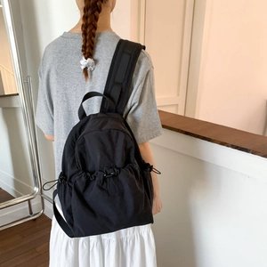 Back view of a model wearing a black nylon backpack with padded shoulder straps