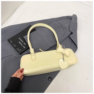 Detail of yellow baguette bag featuring heart pendant and bow charm on a suit background