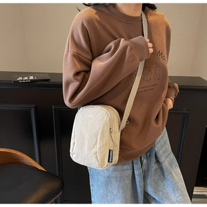 Détail du sac bandoulière en nylon beige avec double fermeture et sangle réglable