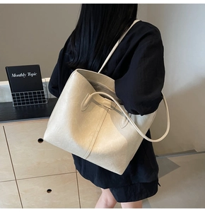Model view of cream beige leather tote bag featuring long shoulder strap and textured finish