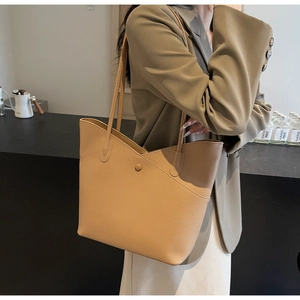 Detail of apricot litchi grain leather texture and magnetic clasp on a tote bag