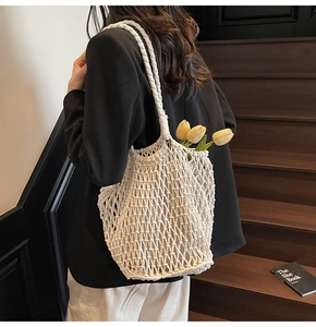 Detail of white hollow knit tote bag with yellow tulip accent on a model's shoulder