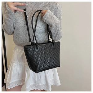 Detail of black woven tote bag with leather texture styled with casual outfit