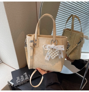 Détail du sac cabas beige avec nœud en dentelle, cœur en perles et cuir texturé