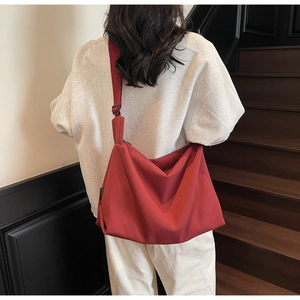 Detail of burgundy canvas tote bag showing draped design and adjustable wide shoulder strap