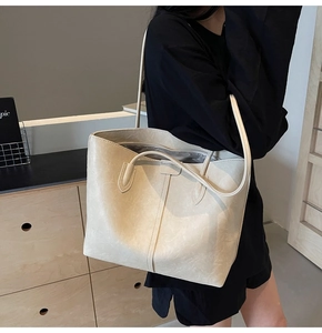 Detailed view of the soft vintage leather texture and zipper closure on a beige tote bag