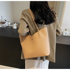 Detailed texture of beige lychee grain leather tote bag worn by a professional model
