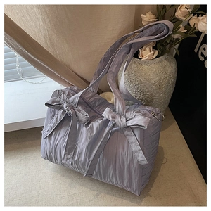 Detail of lavender pleated nylon bucket bag featuring decorative double bows and zip closure