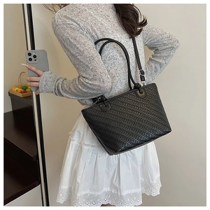 Black woven bucket bag showing detailed herringbone texture and shoulder carry effect