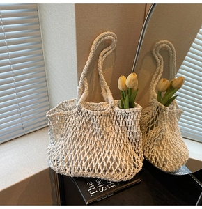 Detail of white macrame knit tote bag with woven mesh texture in sunlight