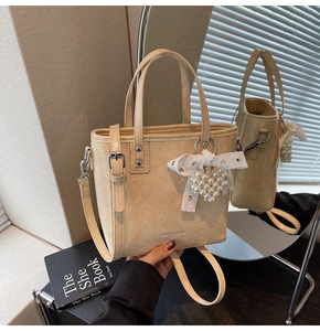 Détail du sac à main crème avec texture plissée et pendentif coeur en dentelle perle