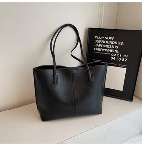 Close-up of black leather tote bag with grainy texture and minimalist vertical stitching